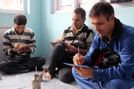 Kashmiri artisans painting on workshop floor