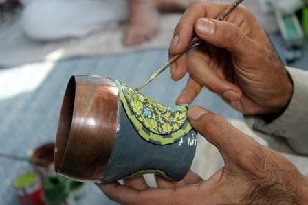 Artisan hand-painting Kashmiri motifs on a copper vessel